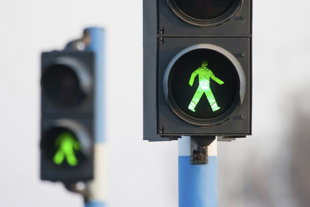 Green lights for pedestrians on two semaphores in traffic.